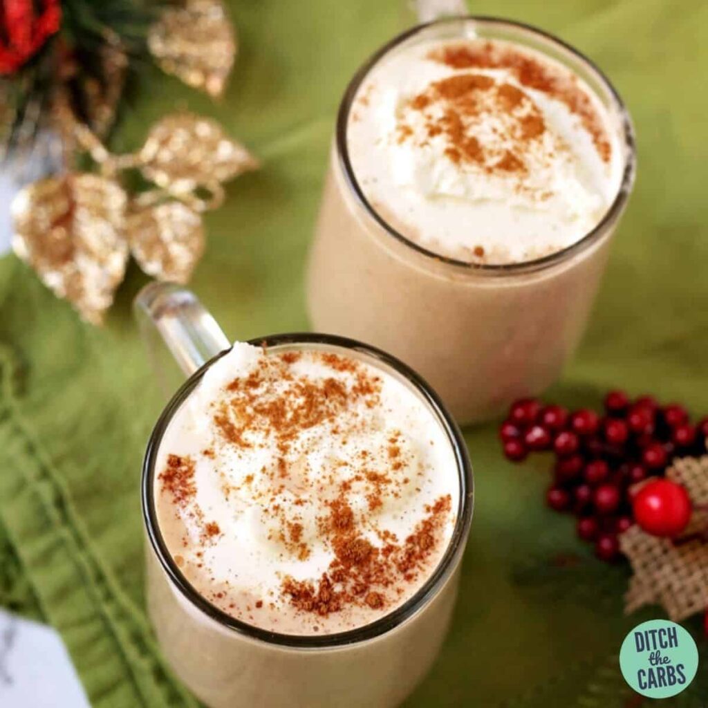 creamy keto eggnog served in two glass coffee mugs with Christmas decorations