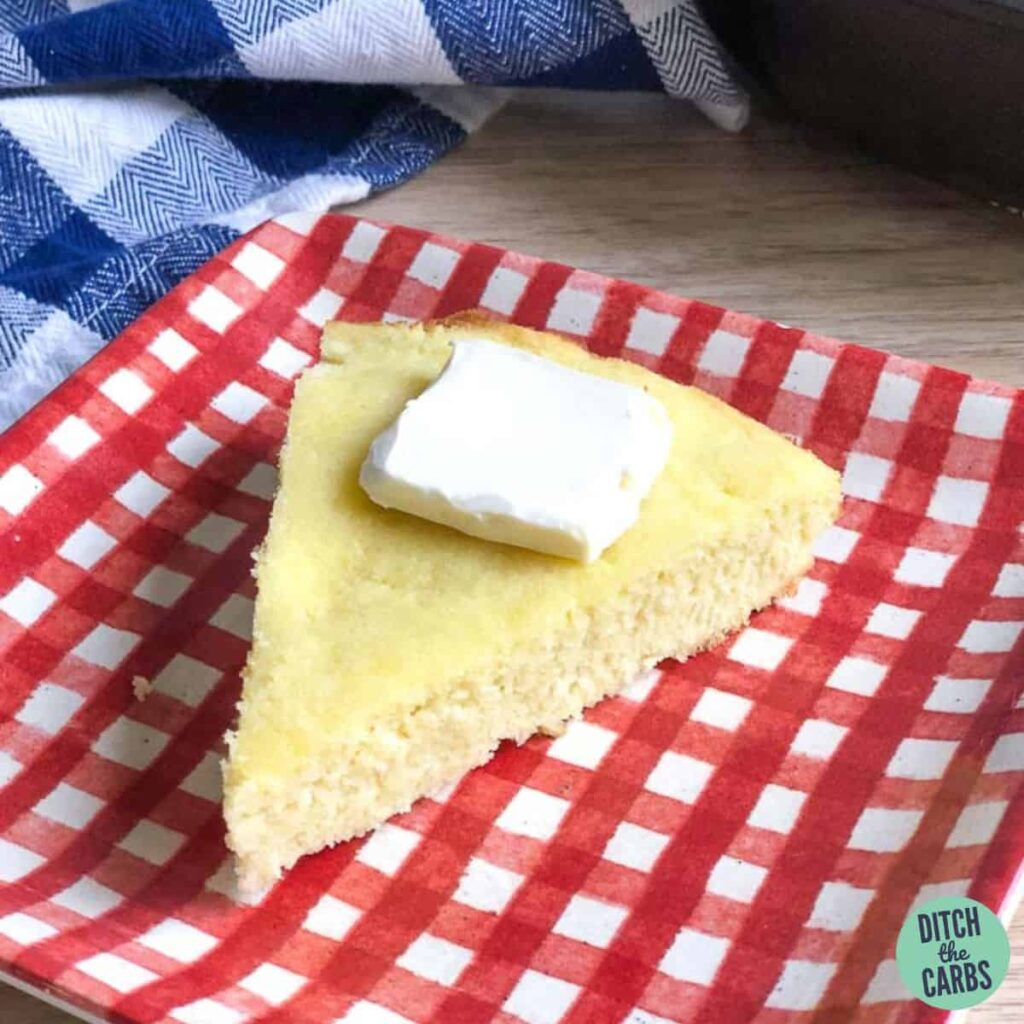 sliced cornbread on a red and white checked plate with butter