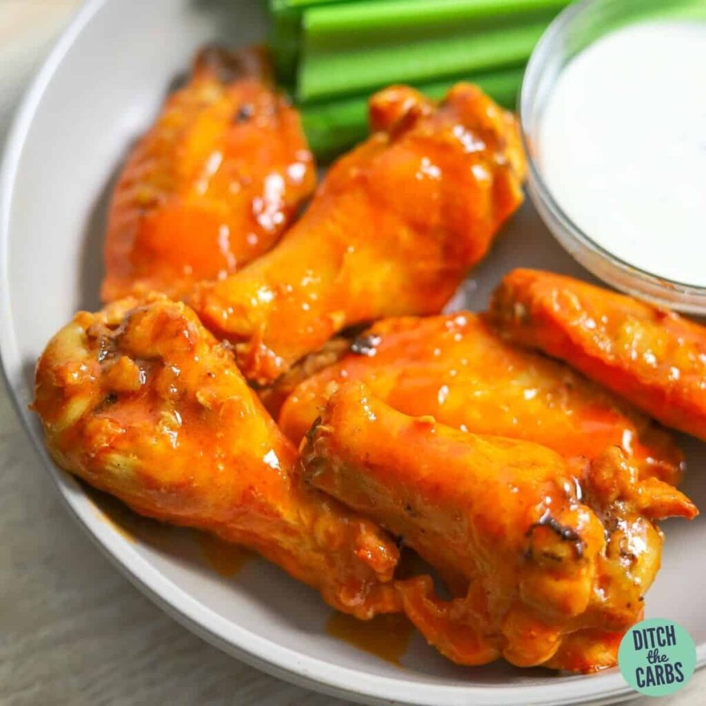 Air Fryer Chicken Wings Tossed in Keto buffalo sauce on a plate with a side of keto ranch and celery.