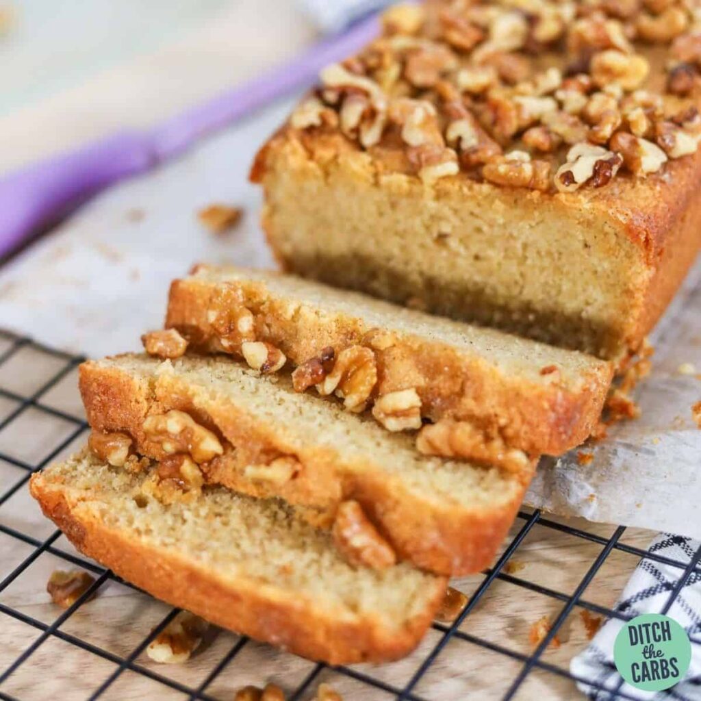 Keto banana bread resting on a white cooling rack. Three slices of bread have been cut.