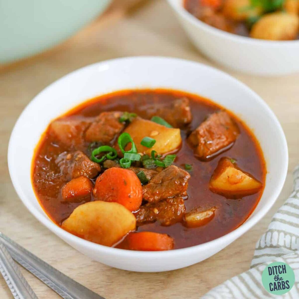 Two bowls of keto beef stew on the counter with the pot of stew in the background.