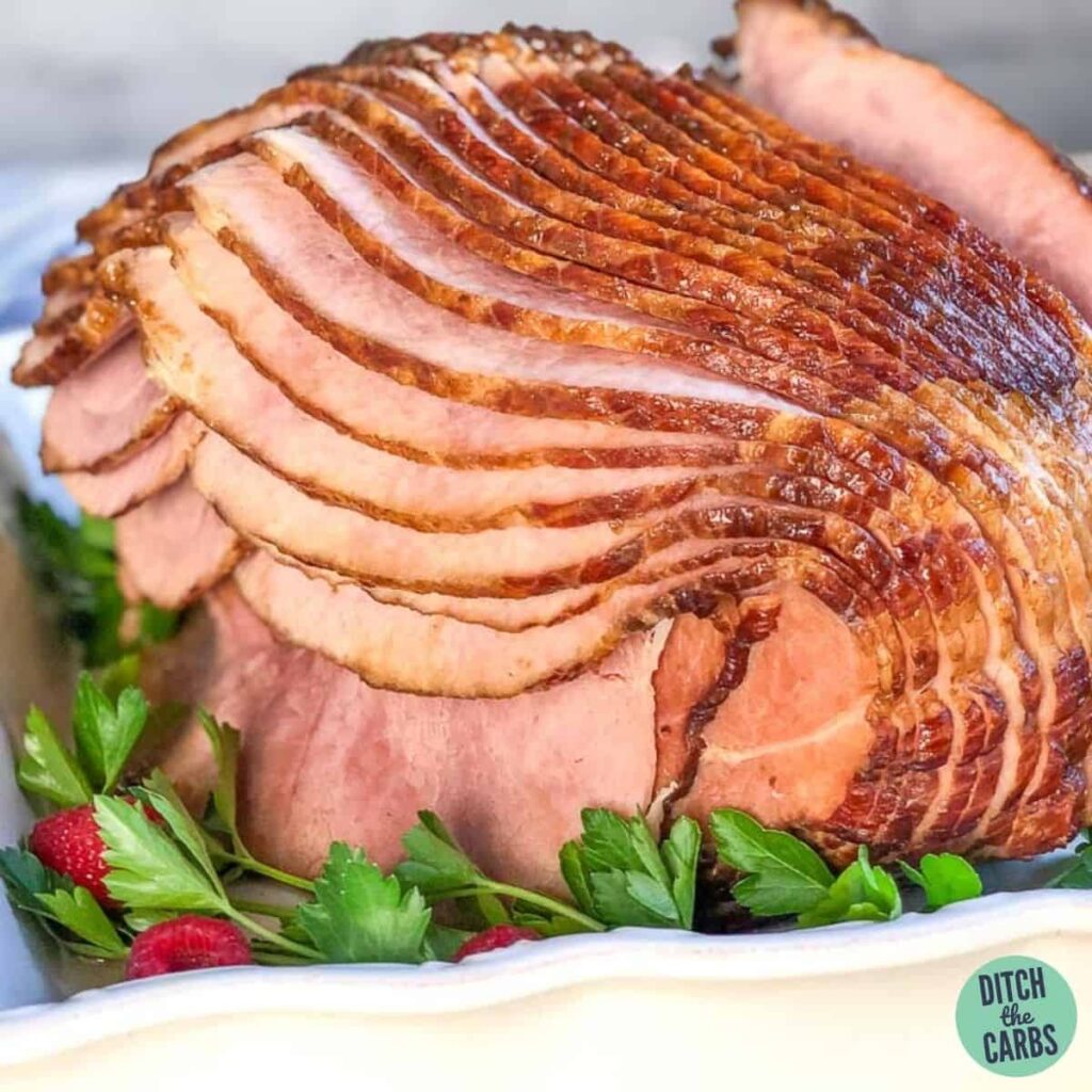 A cooked and glazed sliced ham with herb garnish