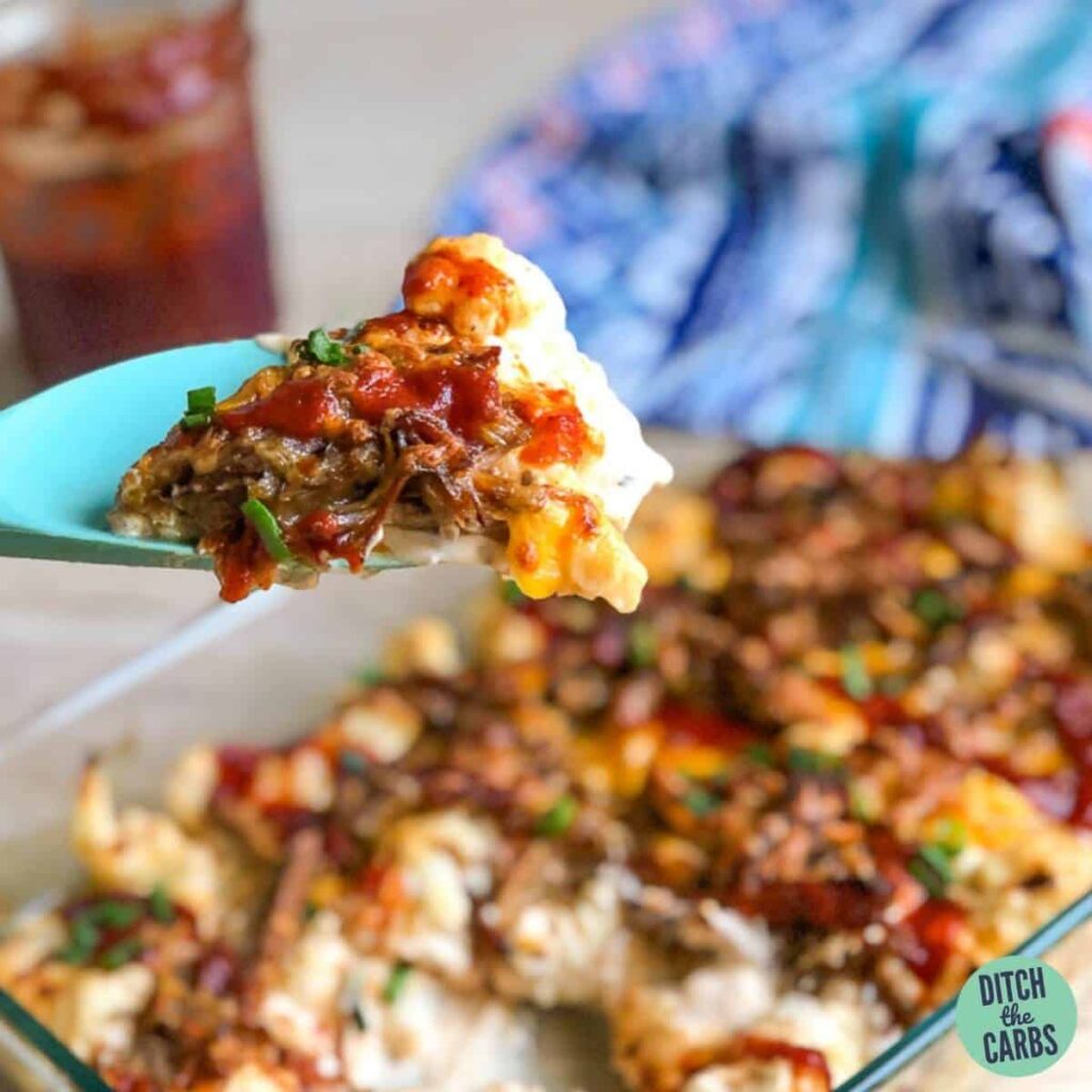 A close up of keto pulled pork mac and cheese being served from a glass serving dish