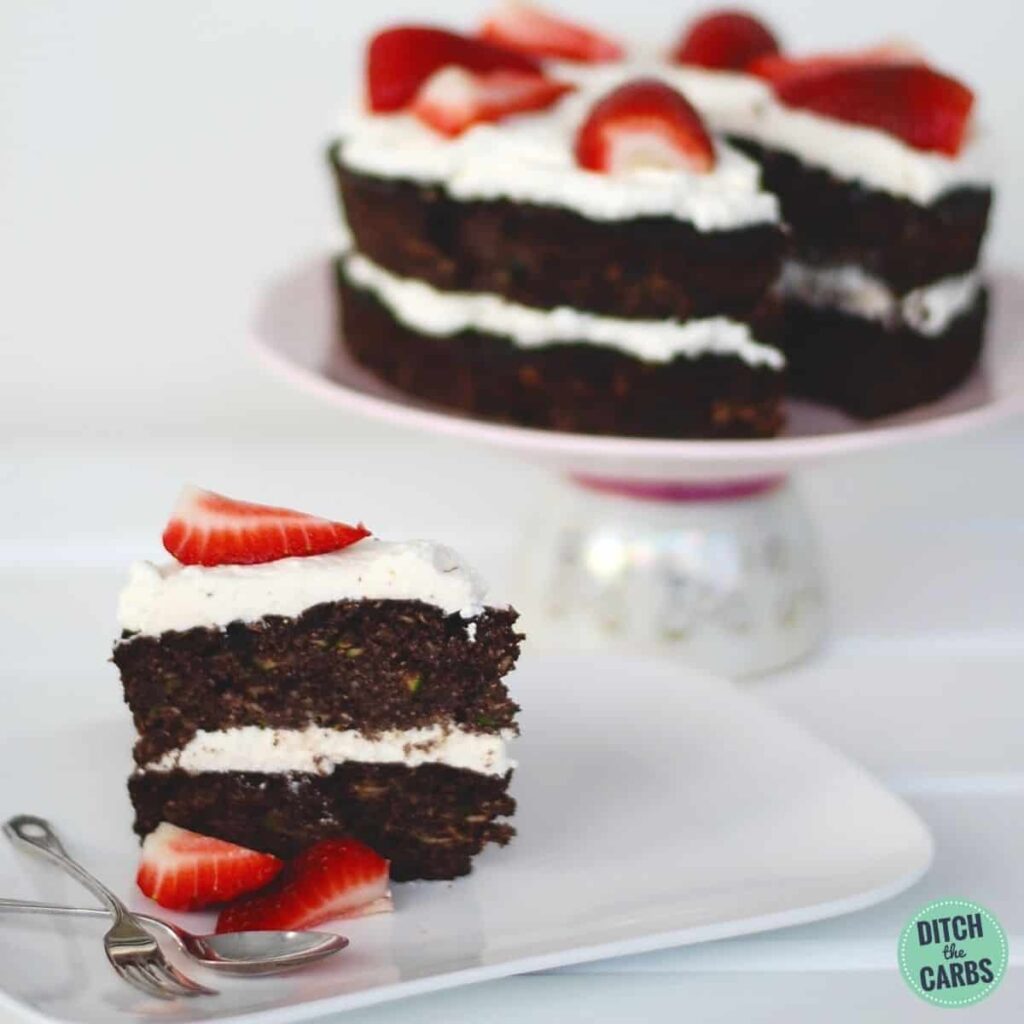 Low-Carb Chocolate Zucchini Cake served with whipped cream and berries on a white plate with strawberries