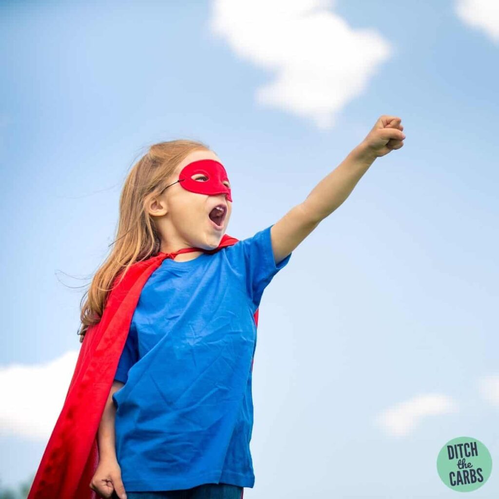 Cute blonde girl dressed and a red cape and hero outfit