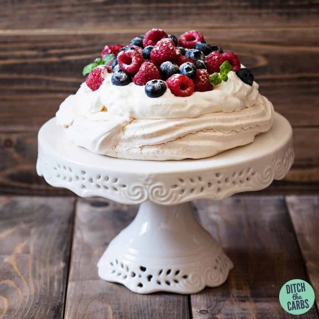 sugar-free pavlova with cream and berries on a serving plate