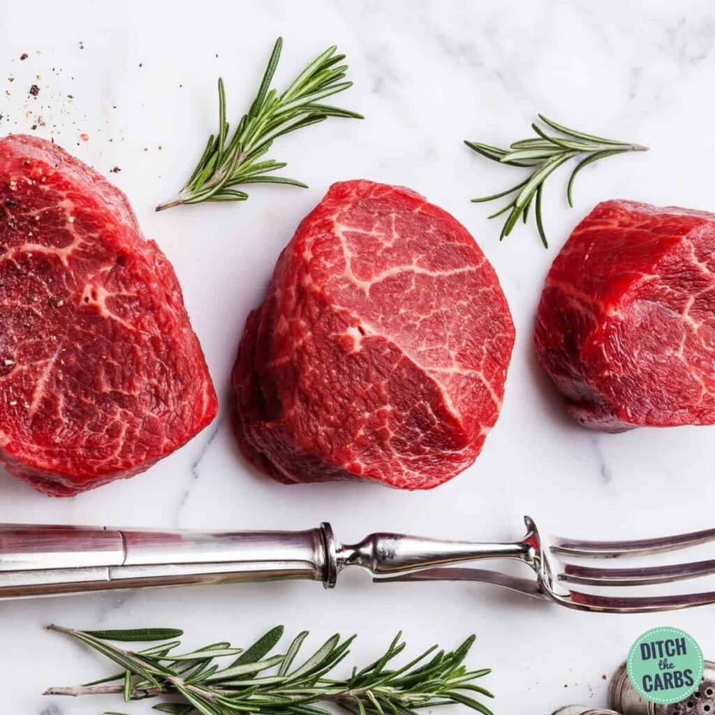 3 raw steaks sitting on a marble slab